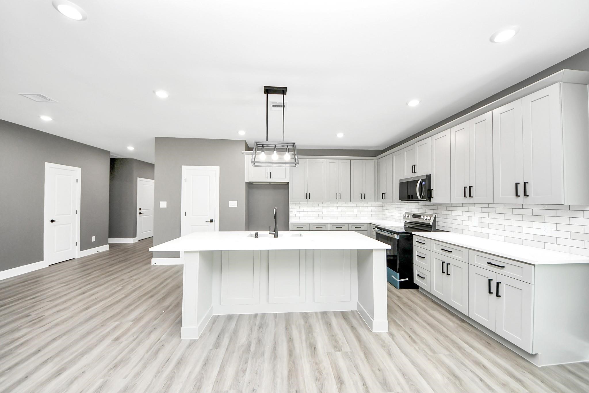 601 Lily Street Prairie View, TX 77484 - Photo 11 of 14 modern kitchen featuring ample cabinets, sleek counter tops, and an open flow into the main living space.