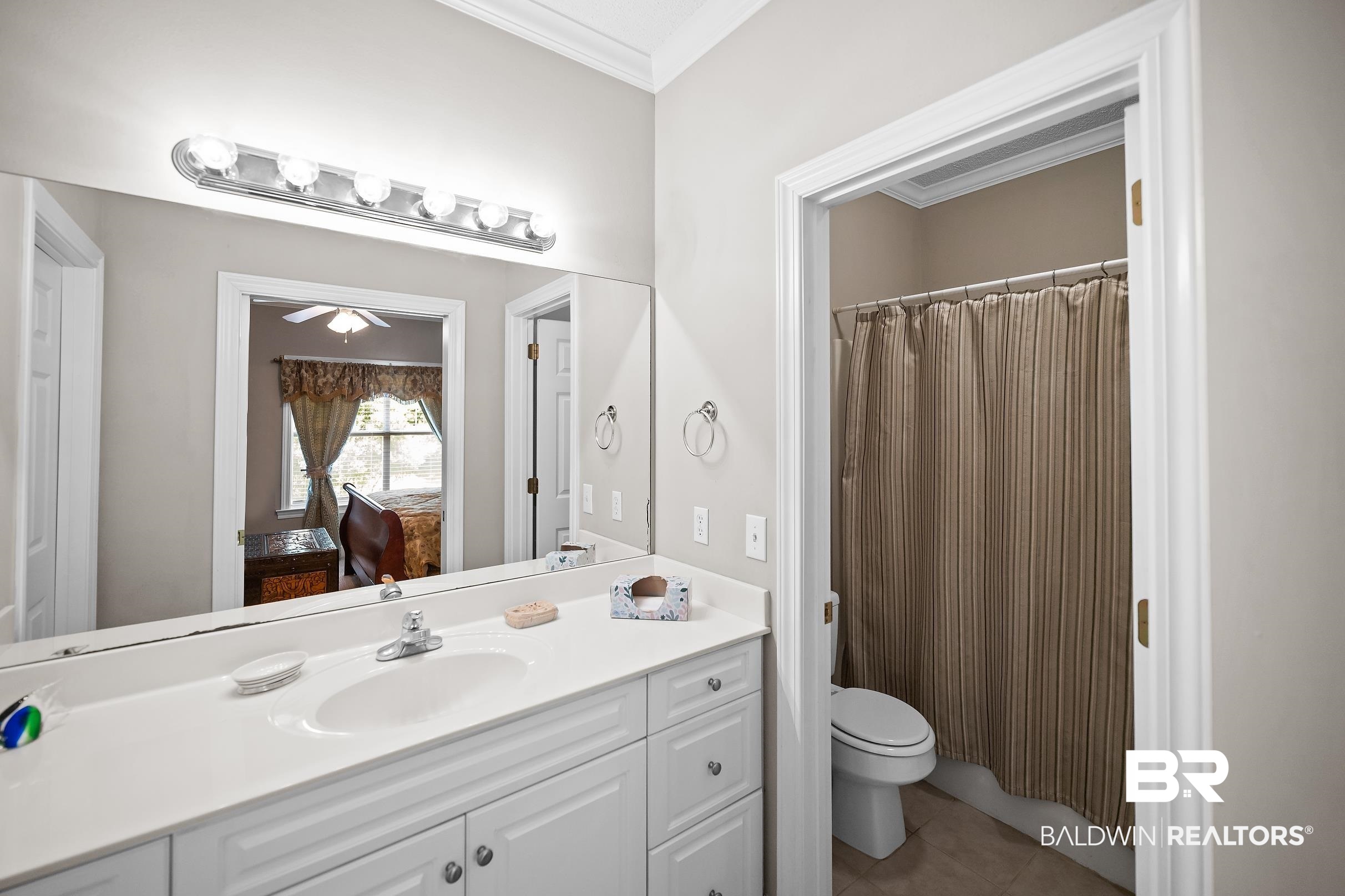 430 West Fort Morgan Road, Unit 704 Gulf Shores, AL 36542 - Photo 14 of 35 Bathroom vanity featuring a white countertop with integrated sink, chrome faucet, and expansive wall-mounted mirror