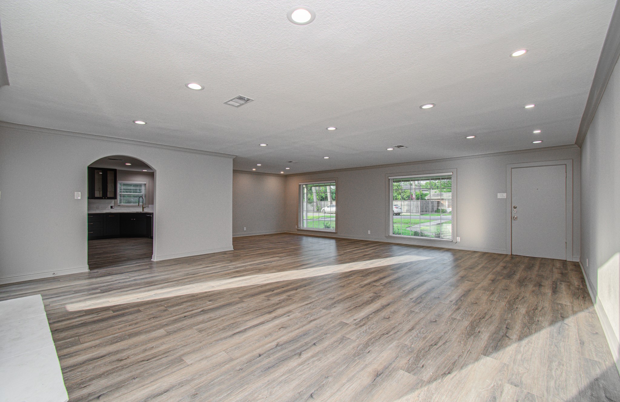 1801 Benbow Way Houston, TX 77080 - Photo 5 of 32 This spacious living area features modern laminate flooring, recessed lighting, and large windows that offer plenty of natural light. An open archway leads to a sleek kitchen, providing a seamless flow for entertaining.