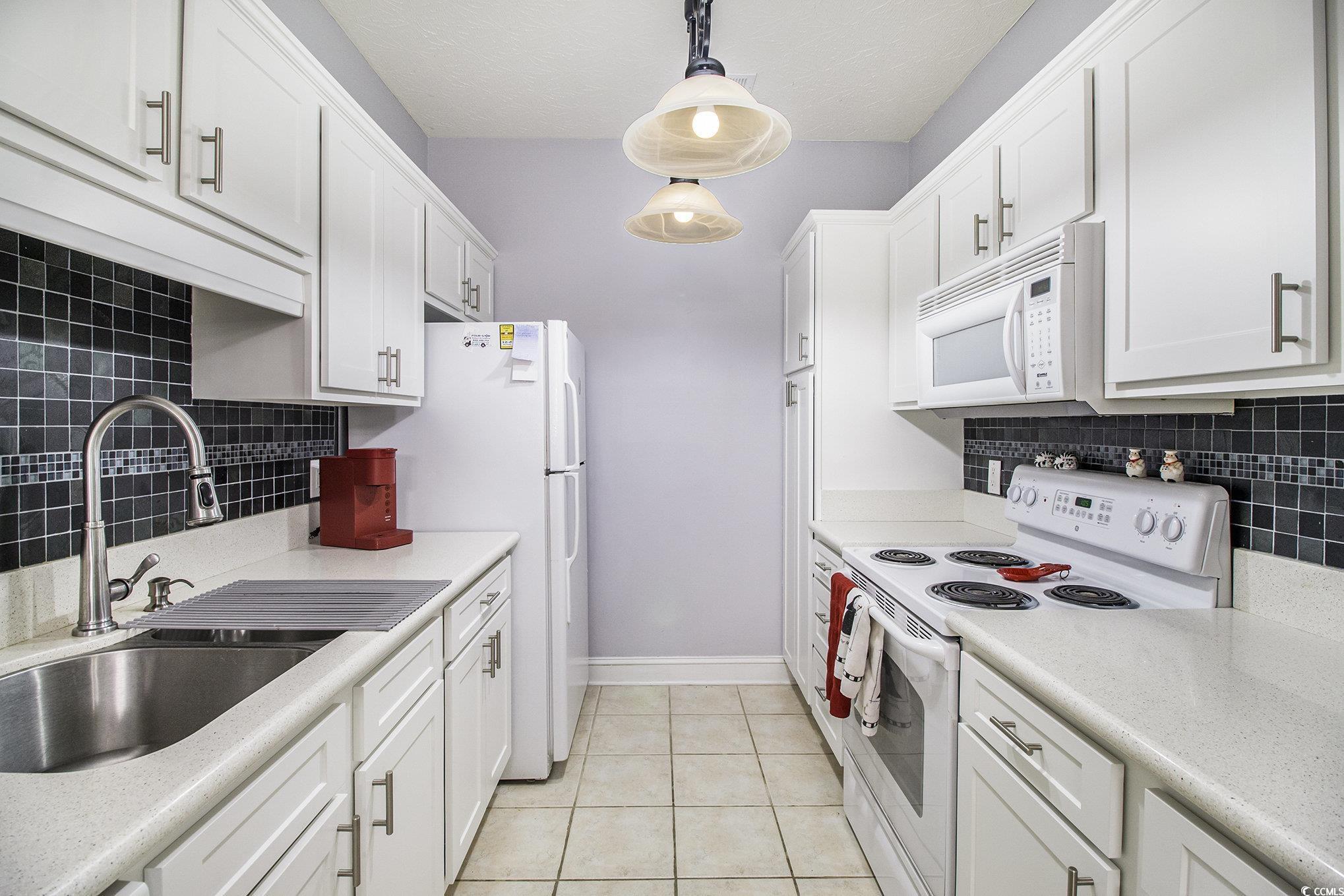 1141 Peace Pipe Place, Unit 101 Myrtle Beach, SC 29579 - Photo 10 of 28 Kitchen featuring white appliances, backsplash, white cabinets, and light countertops