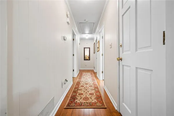 a view of a hallway with wooden floor and a bathroom