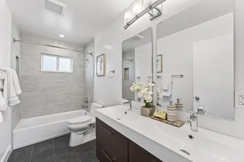 a bathroom with a bathtub shower sink mirror and toilet