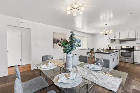 a view of a dining room with furniture a chandelier and kitchen view