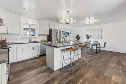 a kitchen with kitchen island granite countertop a sink cabinets and stainless steel appliances