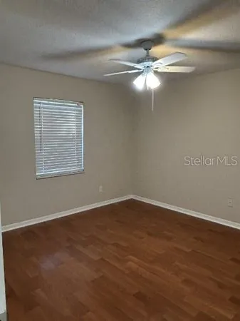 a view of an empty room with window and wooden floor