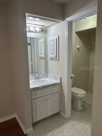 a bathroom with a granite countertop toilet a sink and mirror