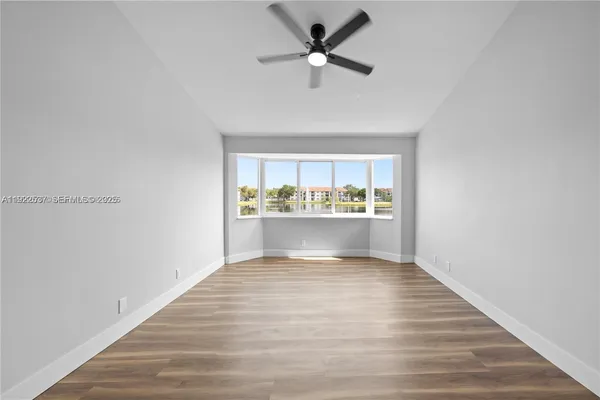 a view of an empty room with window and wooden floor