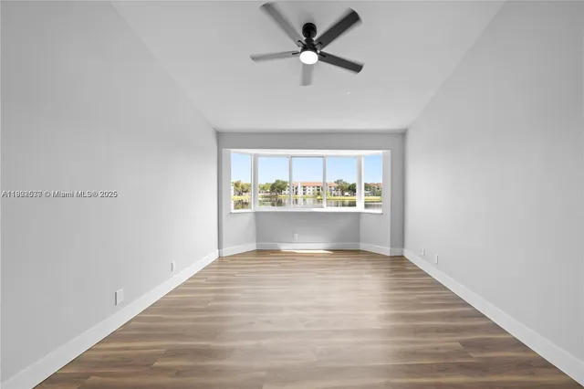 a view of an empty room with window and wooden floor