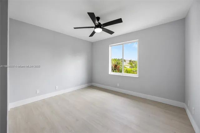 an empty room with ceiling fan and window