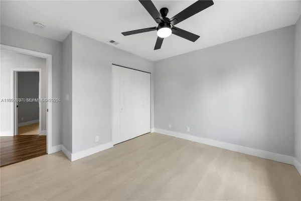 an empty room with wooden floor and a ceiling fan
