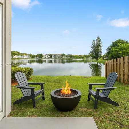 a view of a lake with table and chairs potted plants with lake view