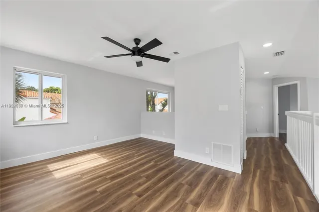 a view of empty room with wooden floor and fan