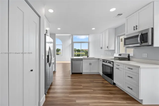 a kitchen with stainless steel appliances kitchen island granite countertop a refrigerator and a stove top oven