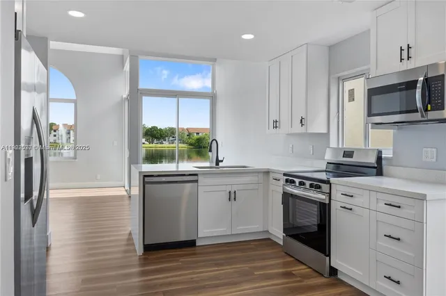 a kitchen with stainless steel appliances white cabinets and a stove top oven