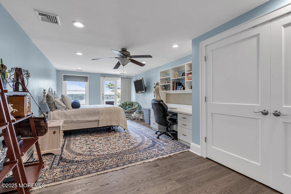 2547 River Road Manasquan, NJ 08736 - Photo 46 of 75 a bedroom with a bed a couch and a bookshelf with wooden floor