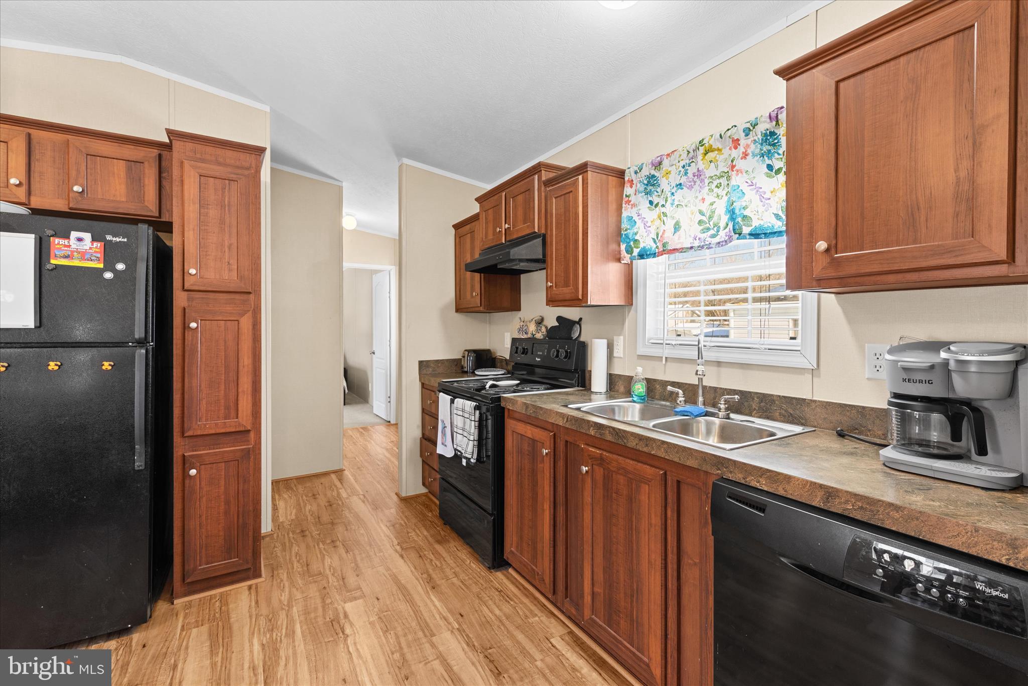 33461 Daisy Street Lewes, DE 19958 - Photo 17 of 42 a kitchen with stainless steel appliances granite countertop a refrigerator a sink dishwasher a stove with wooden cabinets and floor