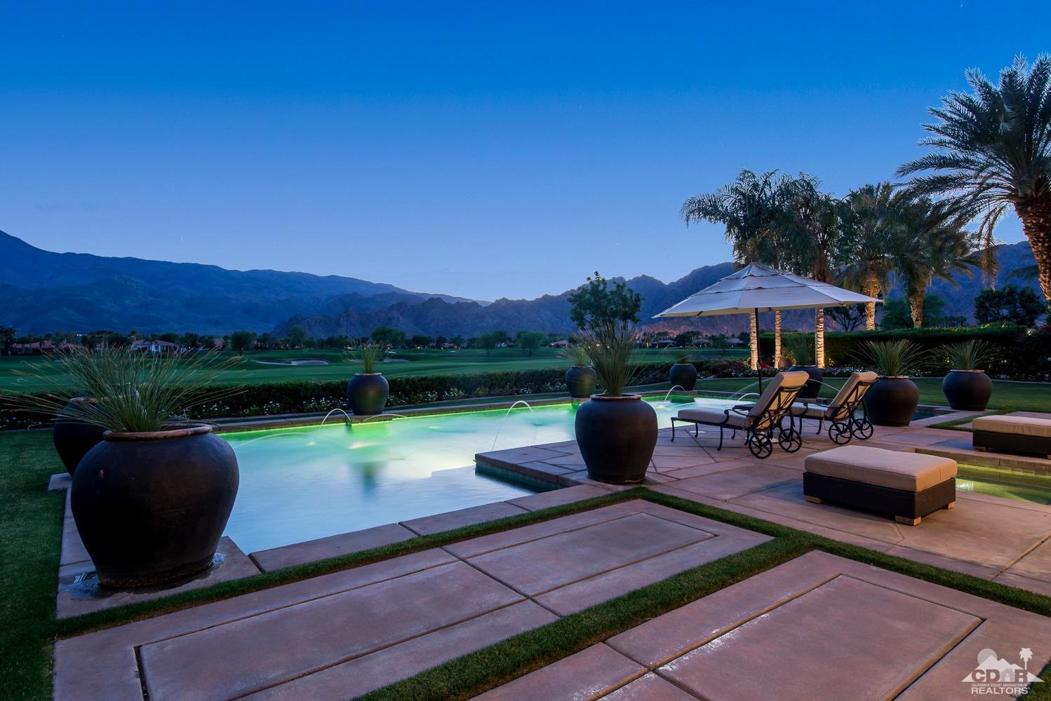 80515 Weiskopf La Quinta, CA 92253 - Photo 5 of 46 a view of a patio with couches table and chairs under an umbrella with a fire pit and a yard