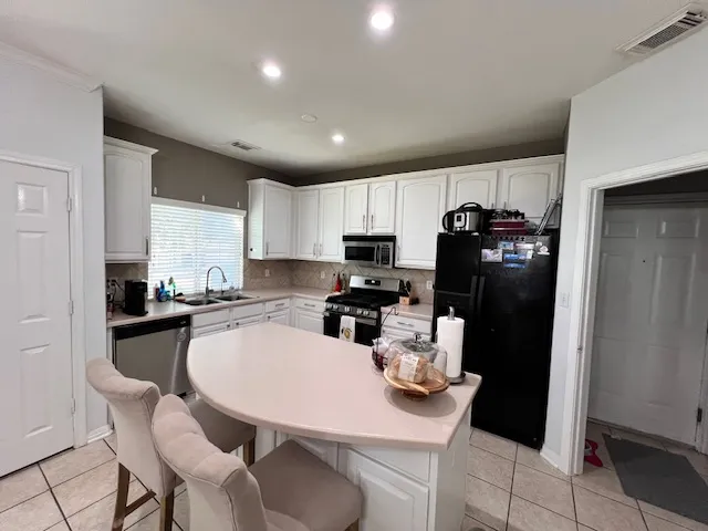 a kitchen with refrigerator and chairs