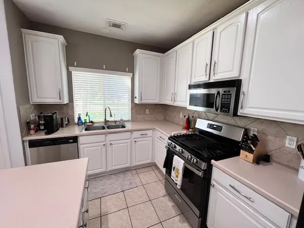 a kitchen with cabinets appliances a sink and a window
