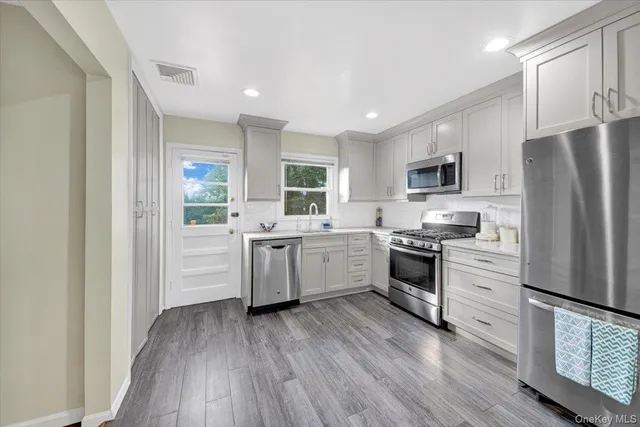 a kitchen with a refrigerator a stove top oven a sink dishwasher and wooden floor