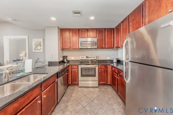 a kitchen with stainless steel appliances granite countertop a refrigerator sink and stove