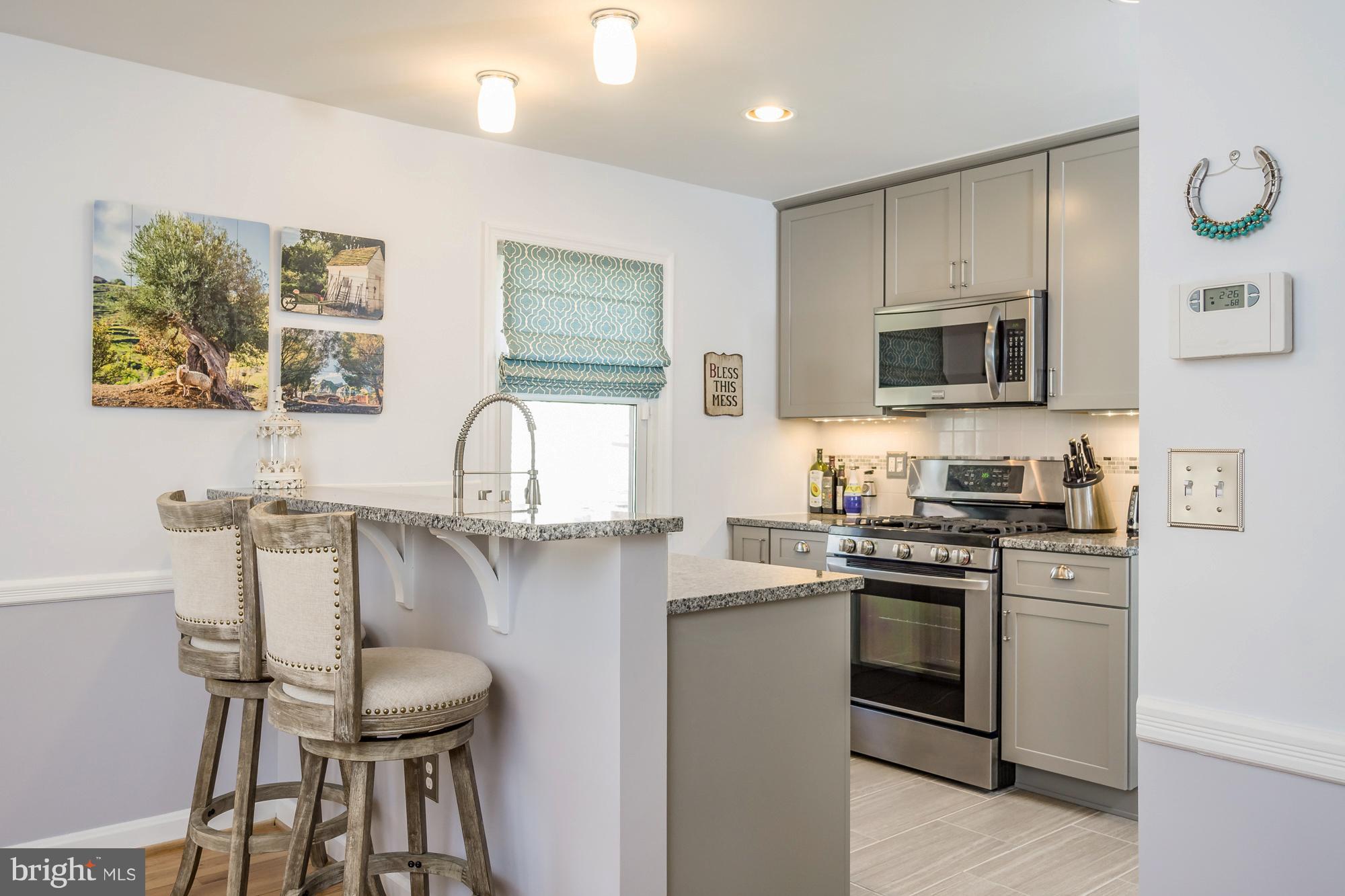 1603 Moffet Road Silver Spring, MD 20903 - Photo 7 of 30 a kitchen with stainless steel appliances granite countertop a stove top oven a sink a dining table and chairs with wooden floor