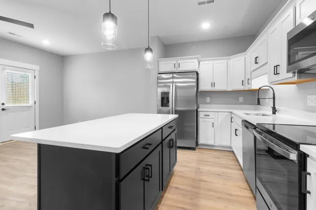 a kitchen with kitchen island a sink dishwasher stove and white cabinets