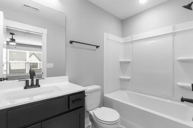 a bathroom with a sink a toilet a mirror and shower