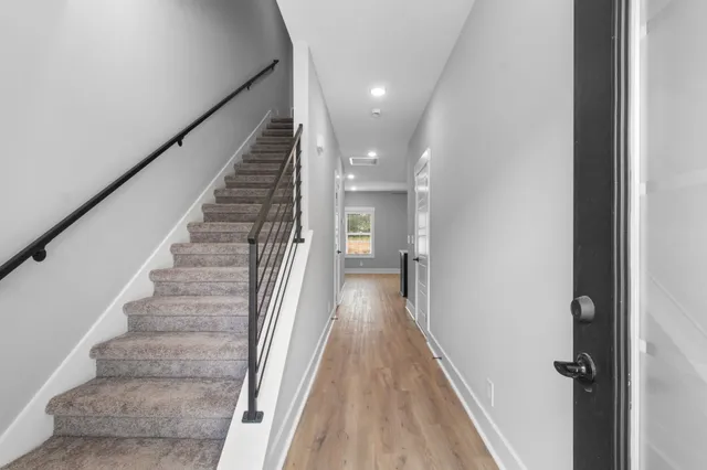 a view of a hallway with wooden floor and staircase