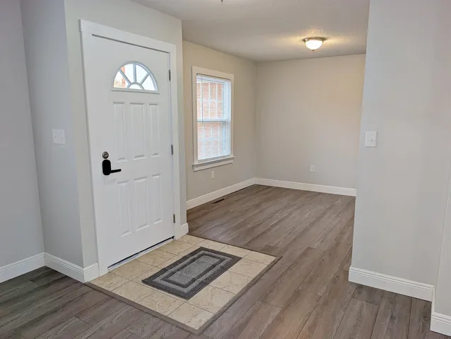 an empty room with wooden floor and window