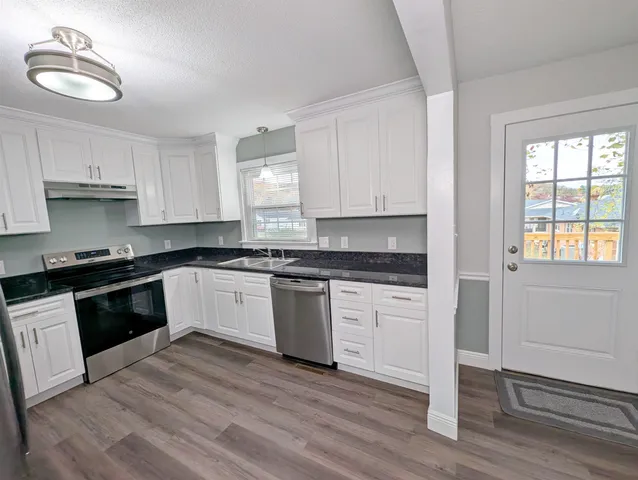 a kitchen with granite countertop wooden floors appliances and cabinets