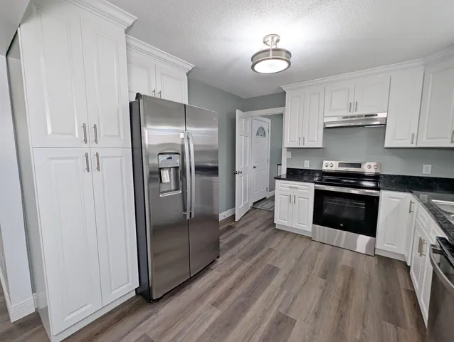 a kitchen with stainless steel appliances a refrigerator a sink and wooden floors