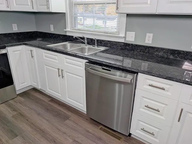 a kitchen with granite countertop white cabinets and sink