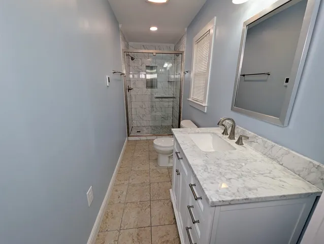 a bathroom with a granite countertop sink a toilet and shower