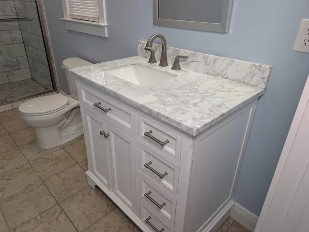 a bathroom with a granite countertop sink a toilet and a mirror
