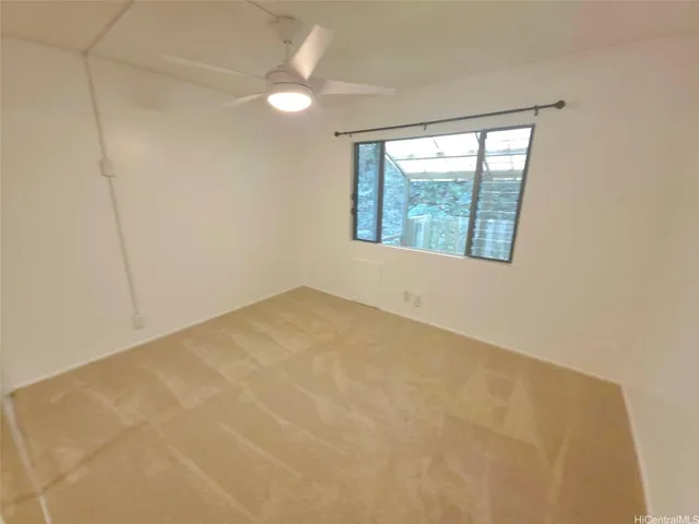 an empty room with windows and fan