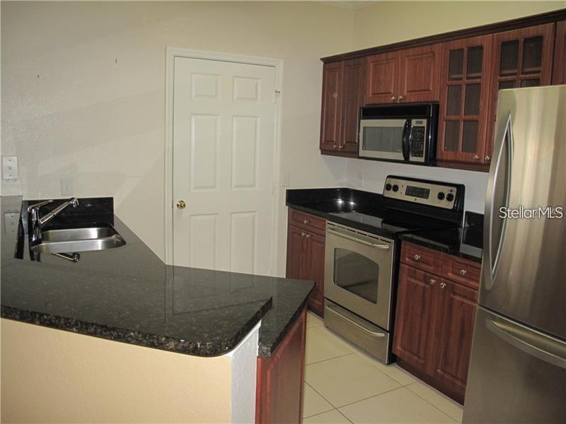3593 Conroy Road, Unit 421 Orlando, FL 32839 - Photo 7 of 28 a kitchen with granite countertop a stove and a microwave