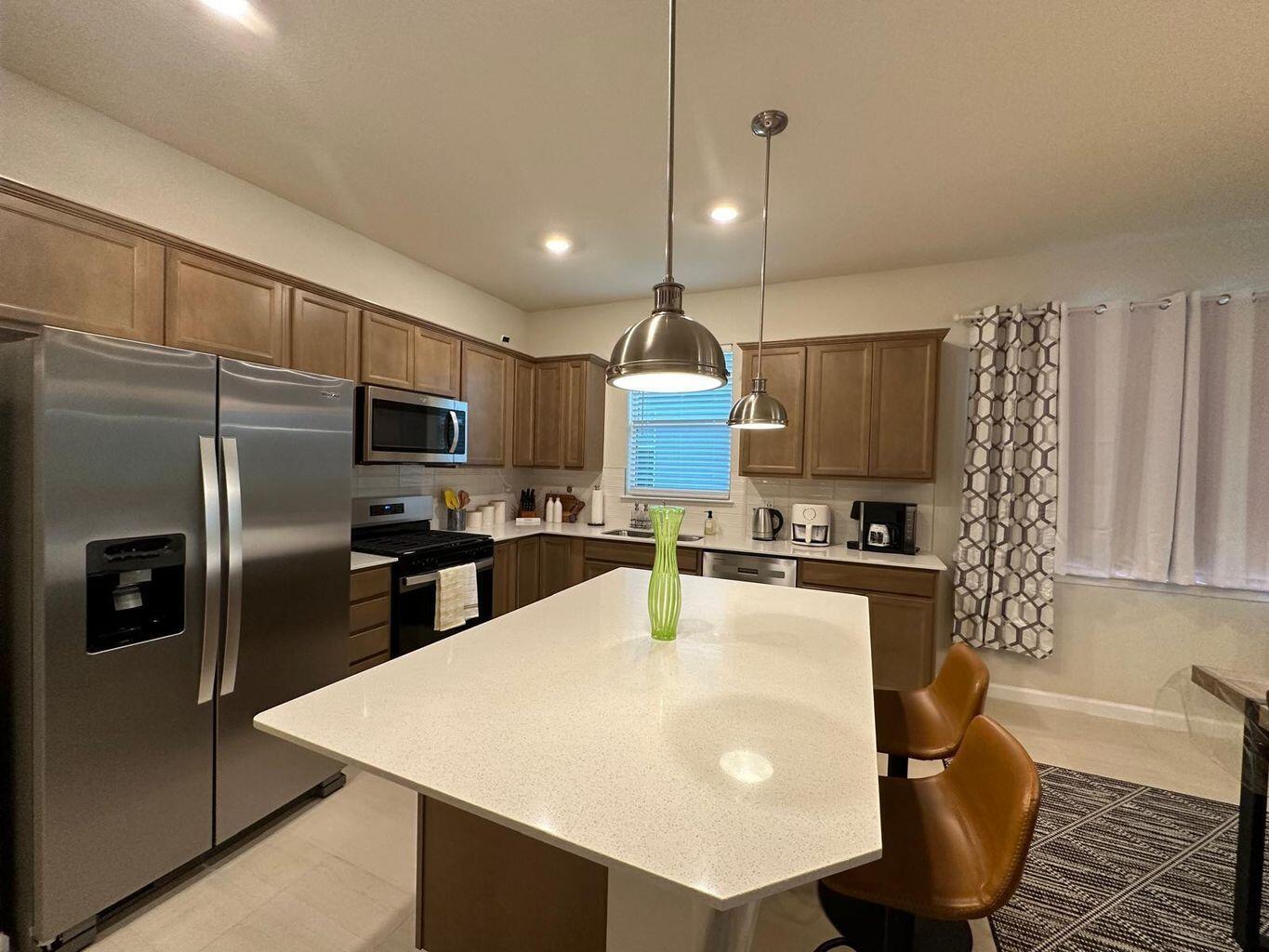 13897 Southwest Gingerline Drive Port St. Lucie, FL 34987 - Photo 45 of 74 a kitchen with stainless steel appliances granite countertop a sink a stove a refrigerator cabinets and chairs