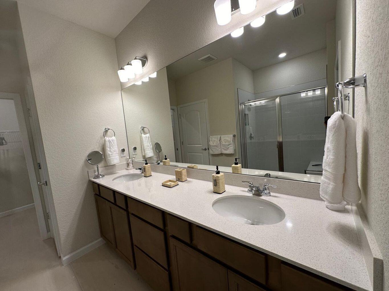 13897 Southwest Gingerline Drive Port St. Lucie, FL 34987 - Photo 63 of 74 a bathroom with double vanity sinks a vanity a lamp and a mirror