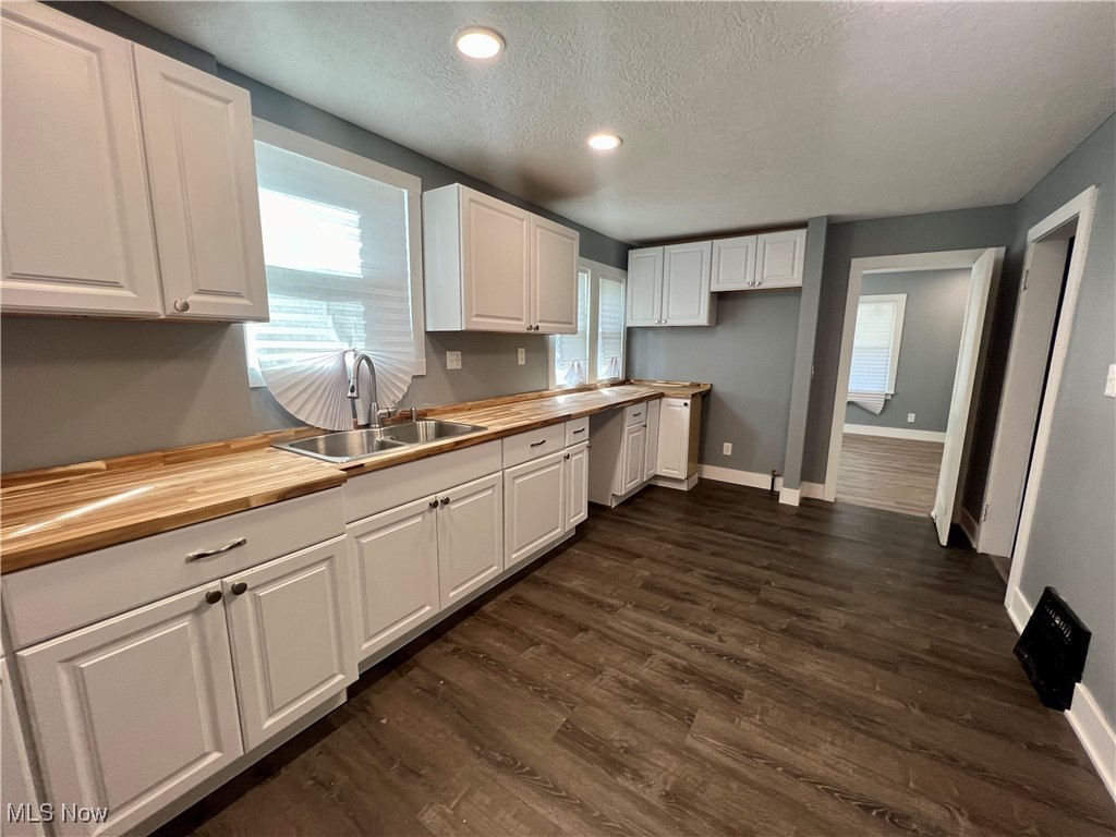 1024 Copley Road Akron, OH 44320 - Photo 11 of 31 Kitchen featuring white cabinets, dark hardwood / wood-style flooring, sink, and wooden counters