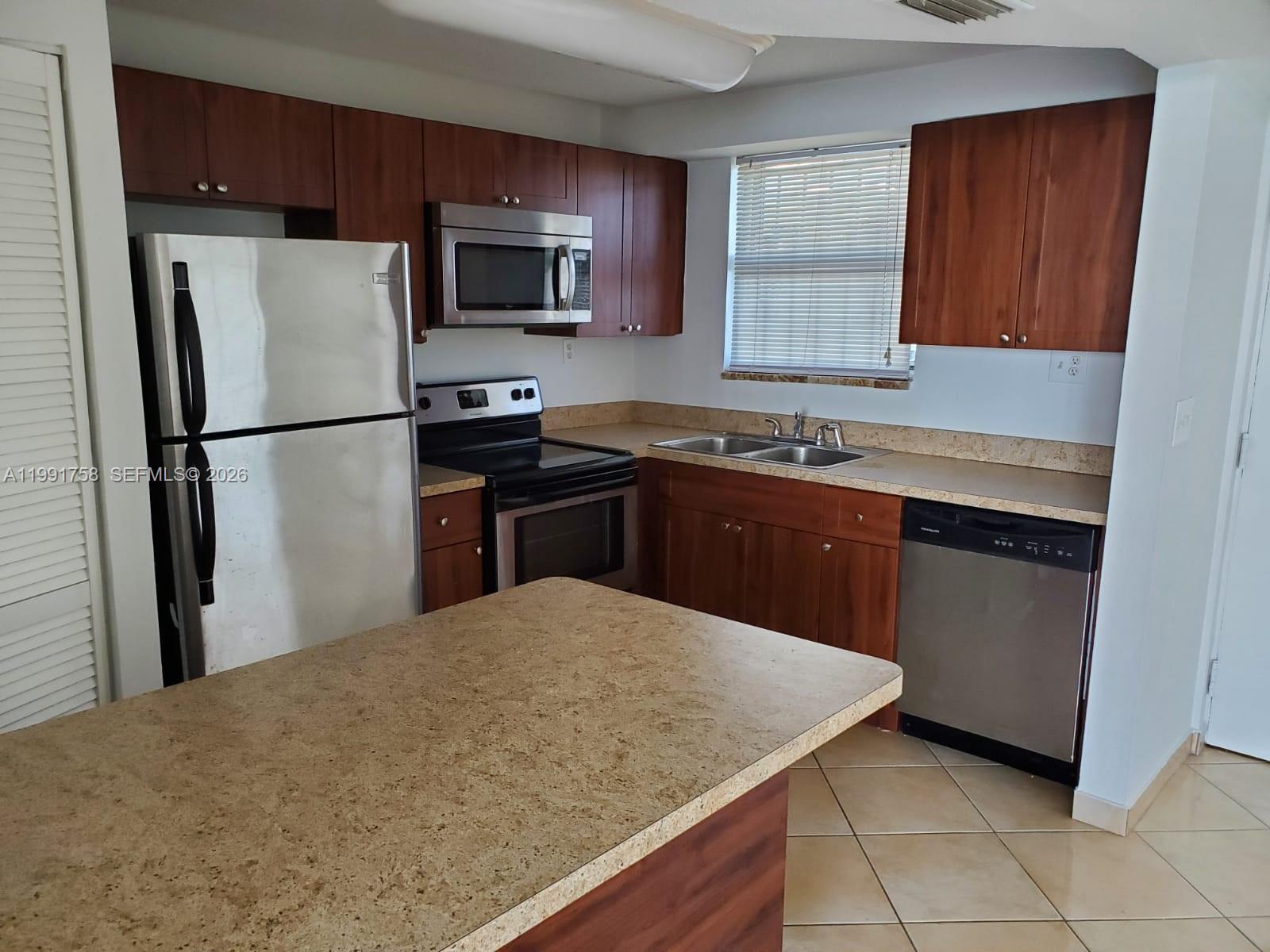 555 Northeast 30th Street, Unit 502 Miami, FL 33137 - Photo 7 of 19 a kitchen with a sink a microwave a refrigerator and cabinets