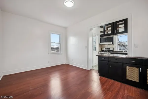 a kitchen with granite countertop wooden floors and black cabinets