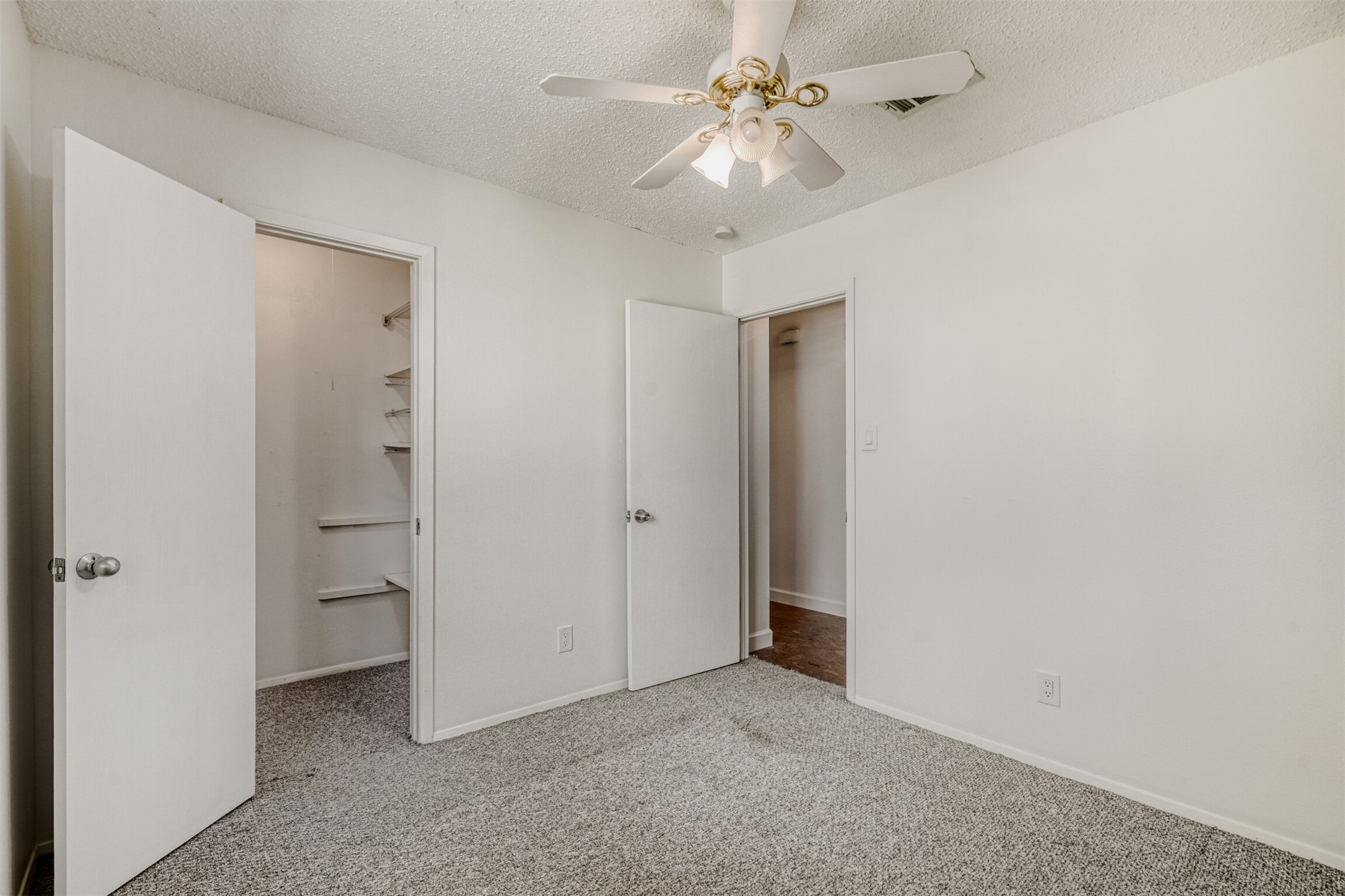 6701 Stage Coach Trail Austin, TX 78745 - Photo 13 of 23 Unfurnished bedroom featuring light colored carpet, a walk in closet, a textured ceiling, and a ceiling fan