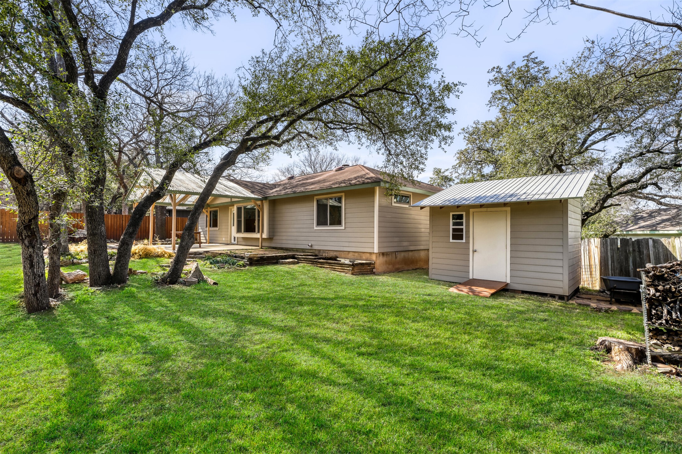 6701 Stage Coach Trail Austin, TX 78745 - Photo 22 of 23 Rear view of property with a fenced backyard, an outdoor structure, a patio area, and a metal roof