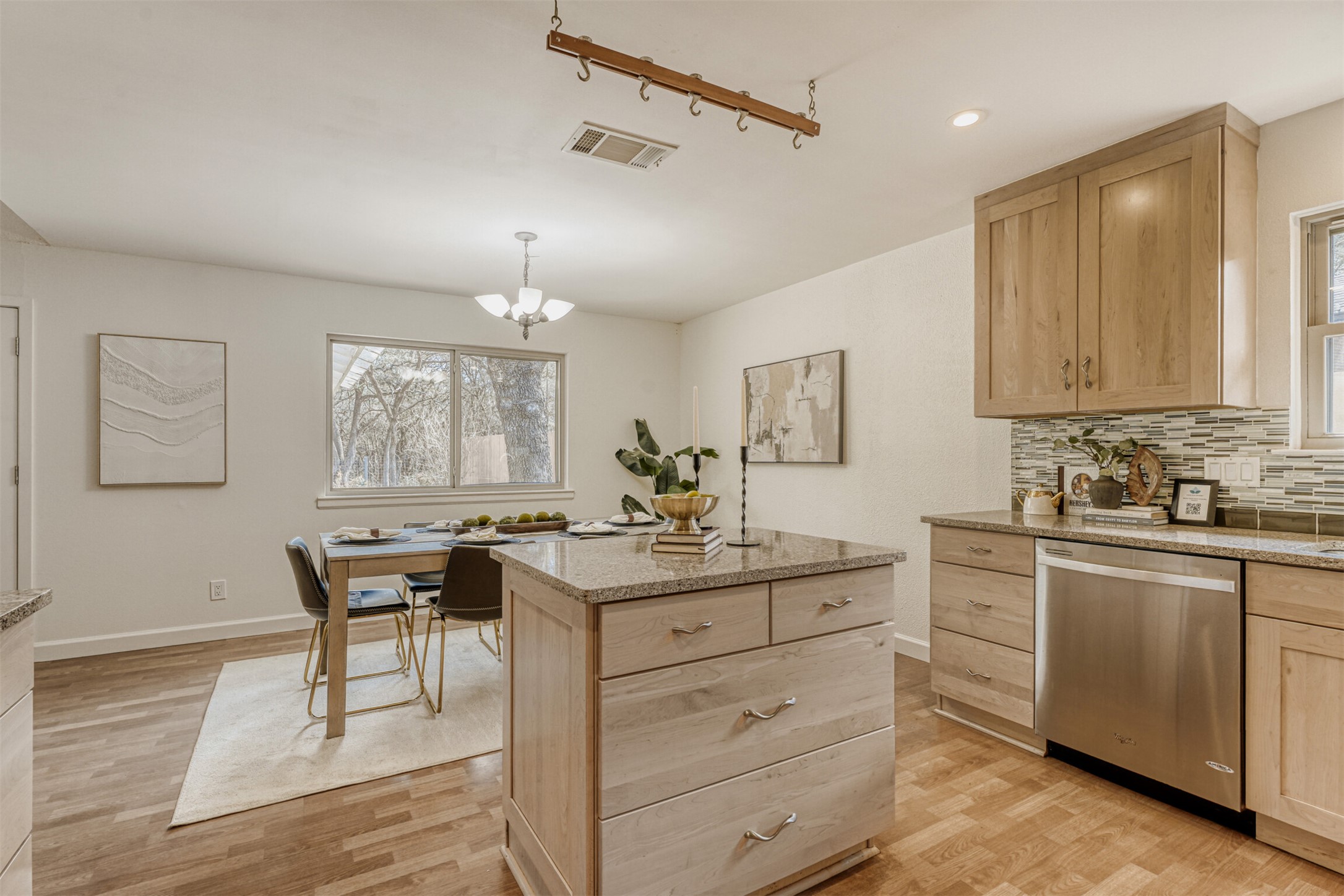 6701 Stage Coach Trail Austin, TX 78745 - Photo 9 of 23 Kitchen with light wood finish cabinets, light stone counters, decorative backsplash, dishwasher, and a chandelier