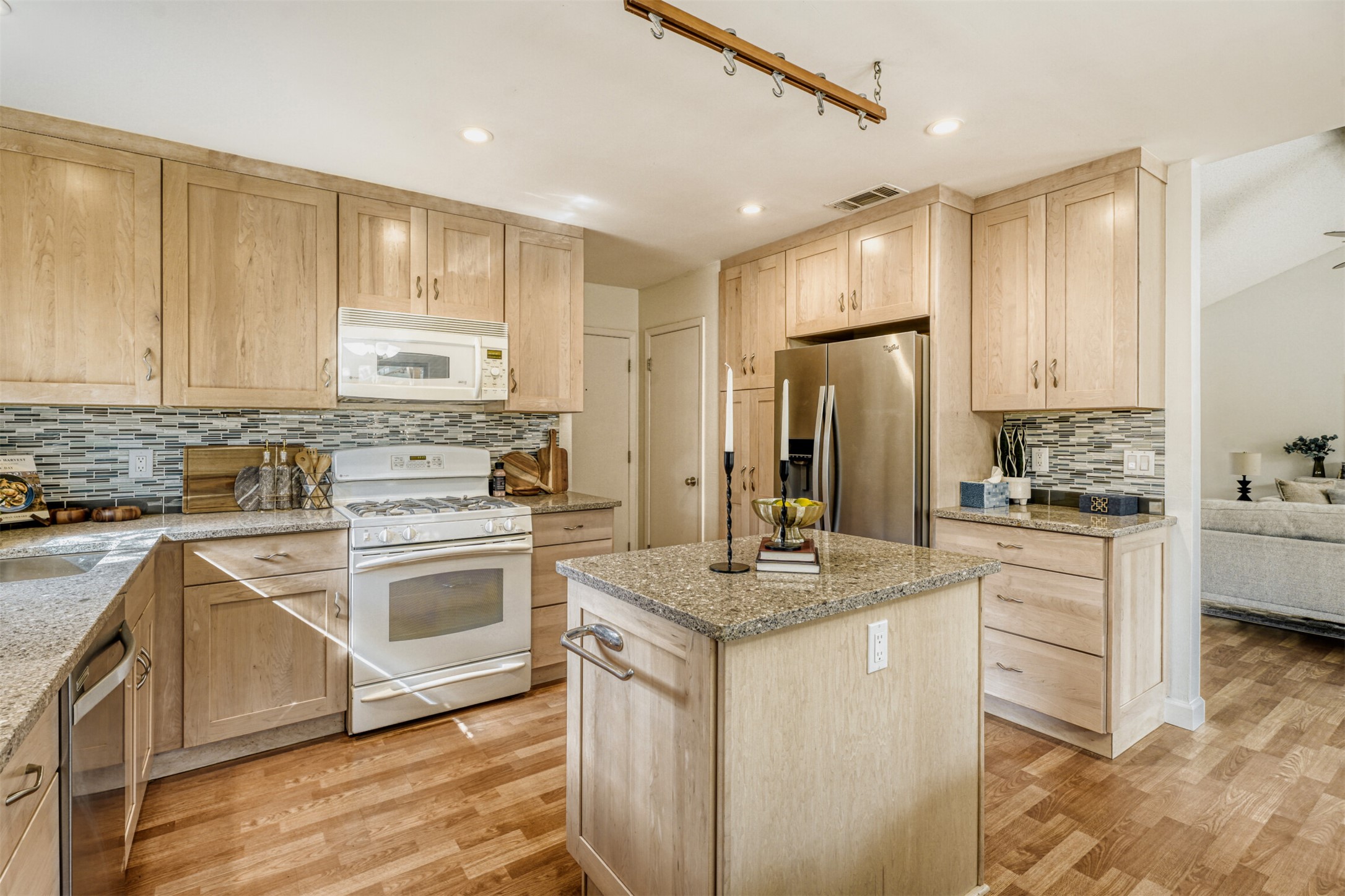 6701 Stage Coach Trail Austin, TX 78745 - Photo 10 of 23 Kitchen featuring light wood finish cabinets, stainless steel appliances, light stone counters, a center island, and light wood-style floors