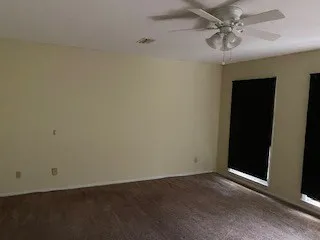an empty room with a ceiling fan and a window