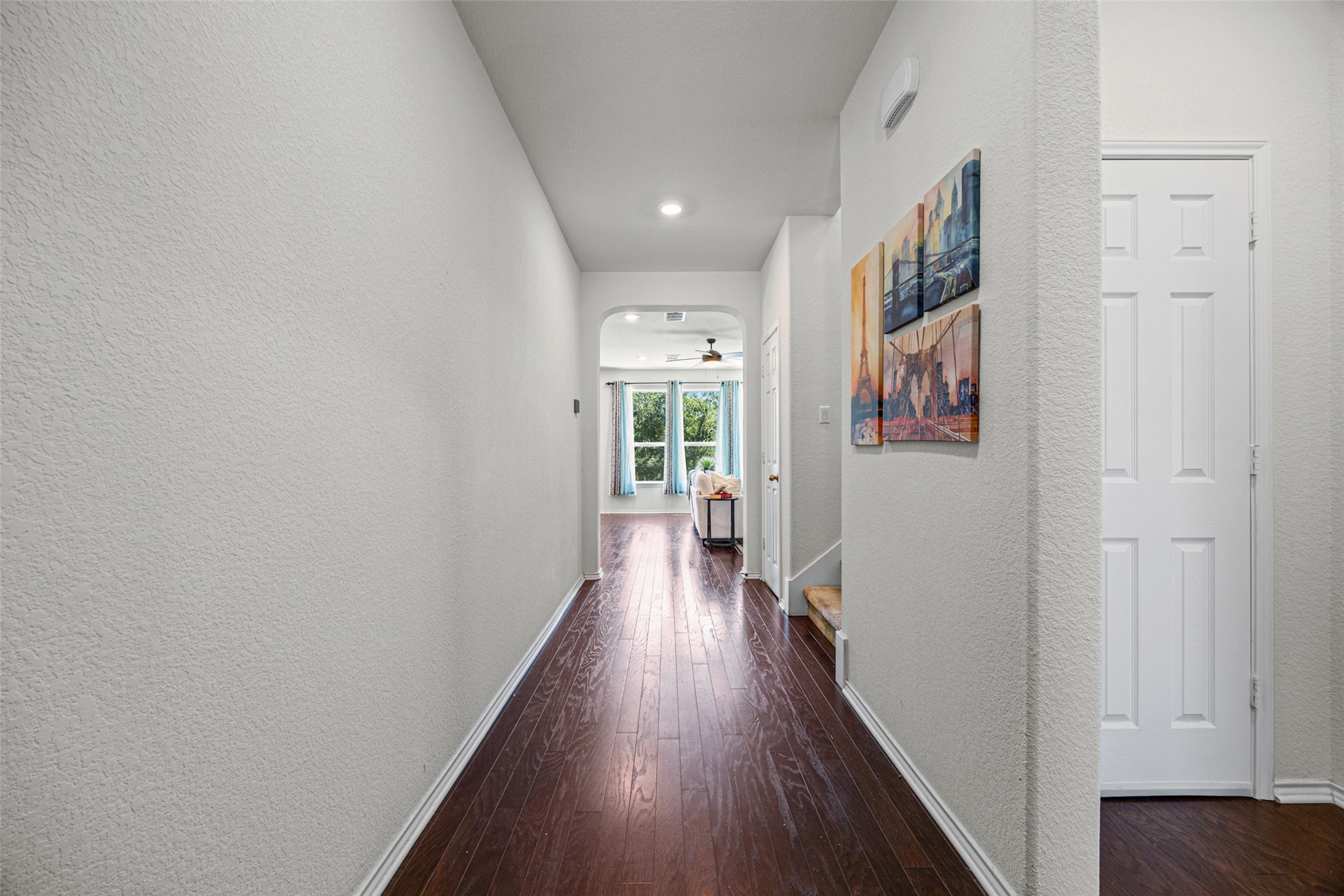 2471 Sunrise Road, Unit 64 Round Rock, TX 78664 - Photo 19 of 32 A well-lit corridor with rich wood flooring leads to a spacious living area, offering a seamless flow through the home.