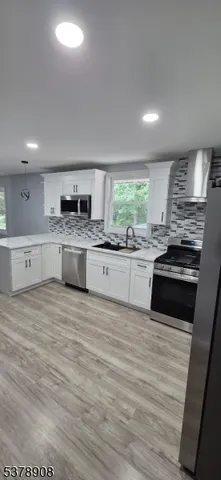 a large kitchen with granite countertop a stove top oven a sink dishwasher and a refrigerator