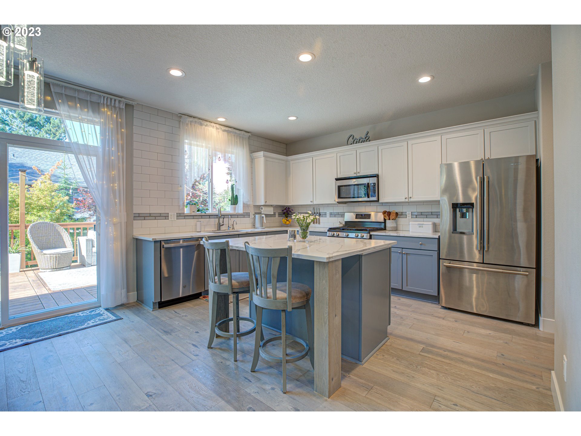 6055 Southeast 28th Street Gresham, OR 97080 - Photo 22 of 48 a kitchen with a refrigerator a microwave a stove a sink and a dining table with wooden floor